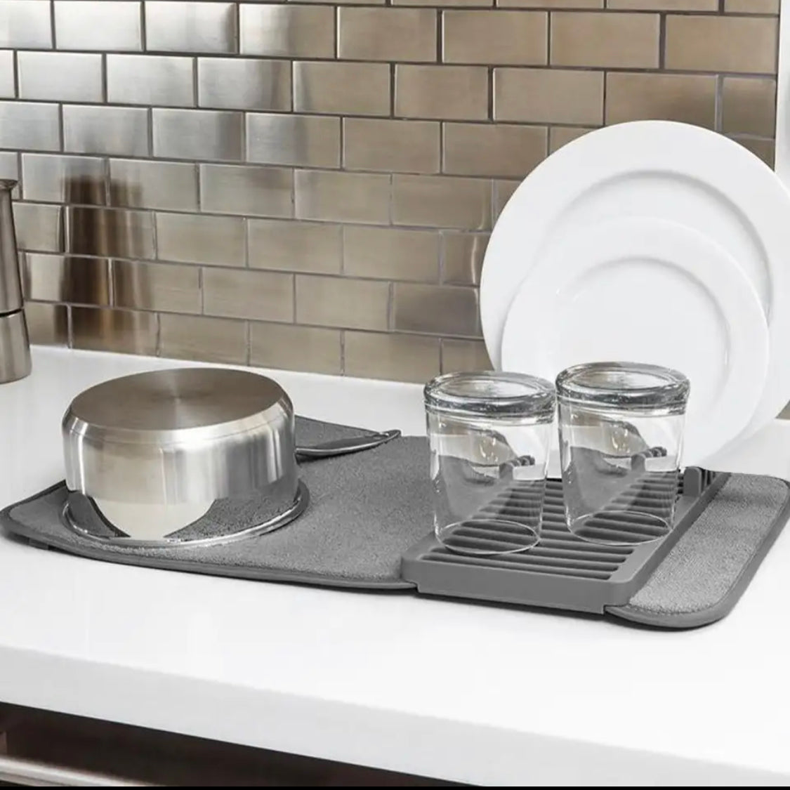 Gray dish drying rack with pots, pans, and glasses on a kitchen counter.