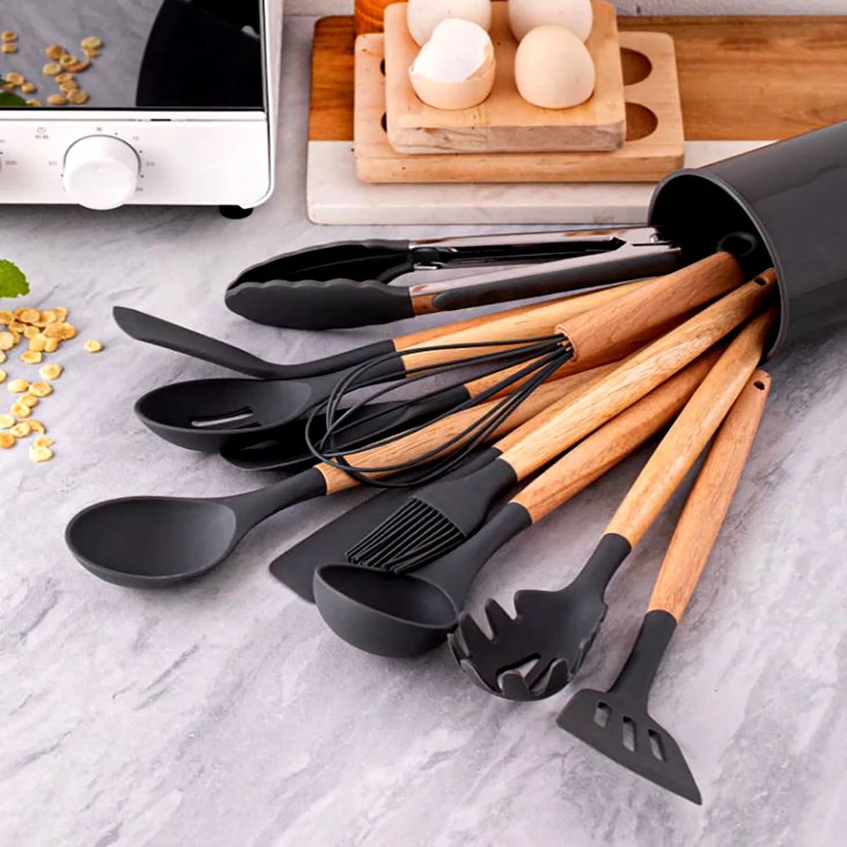 Set of black and wooden kitchen utensils on a gray surface with eggs and cereal in the background. silicone wooden handle kitchen utensil set Pakistan.