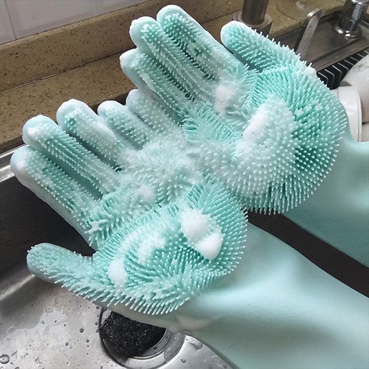 Green silicone dishwashing gloves with textured surface in a kitchen sink.