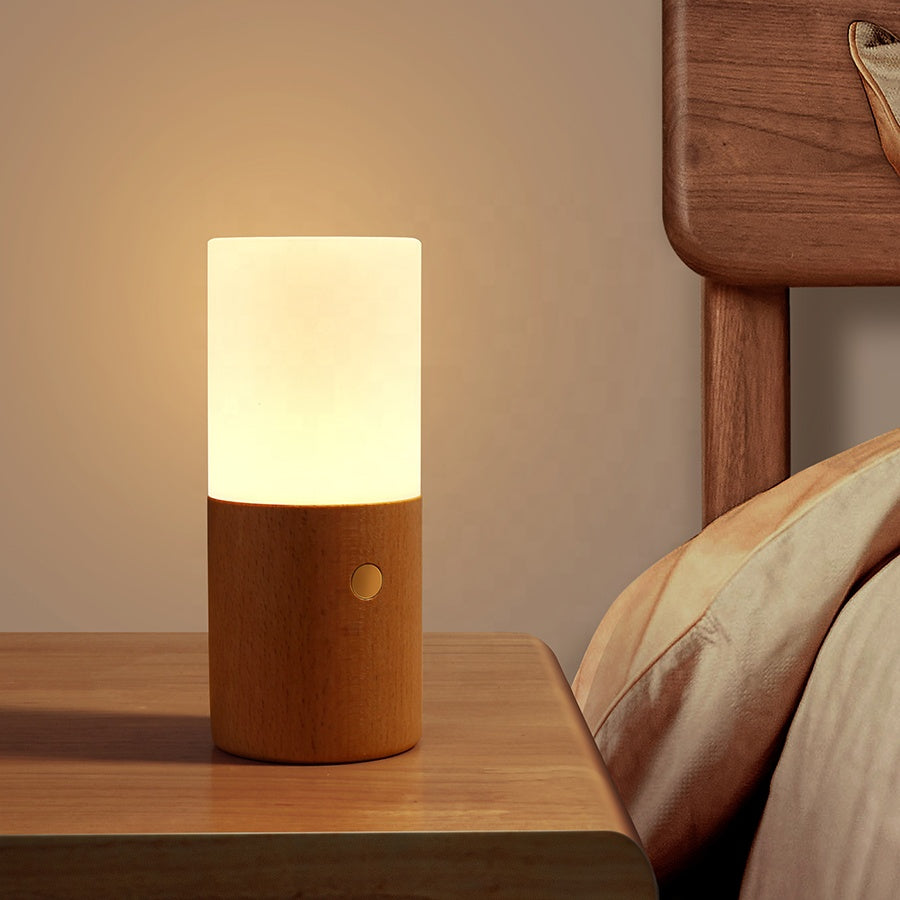 Wooden table lamp with a white shade on a wooden nightstand next to a bed. rechargeable RGB wooden table lamp Pakistan, gravity flip night light USB‑C.