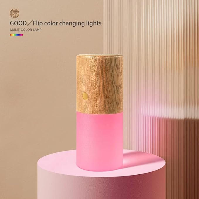 Color-changing lamp with wooden top and pink base on a pink platform against a beige background. rechargeable RGB wooden table lamp Pakistan, gravity flip night light USB‑C.