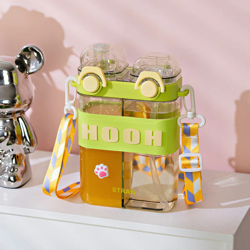 Clear water bottle with green strap and colorful accents on a pink background. HOOH water pot 800ml, double chamber bottle with strap, kids crossbody water bottle, two drinks bottle, HOOH split drink bottle, dual chamber water bottle, 2‑in‑1 water bottle Pakistan.