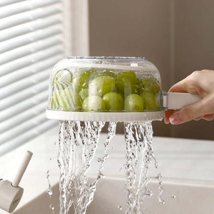 Hand washing green grapes under running water in a transparent container. knob switch colander, foldable strainer bowl, small kitchen gadget, drain basket with lid