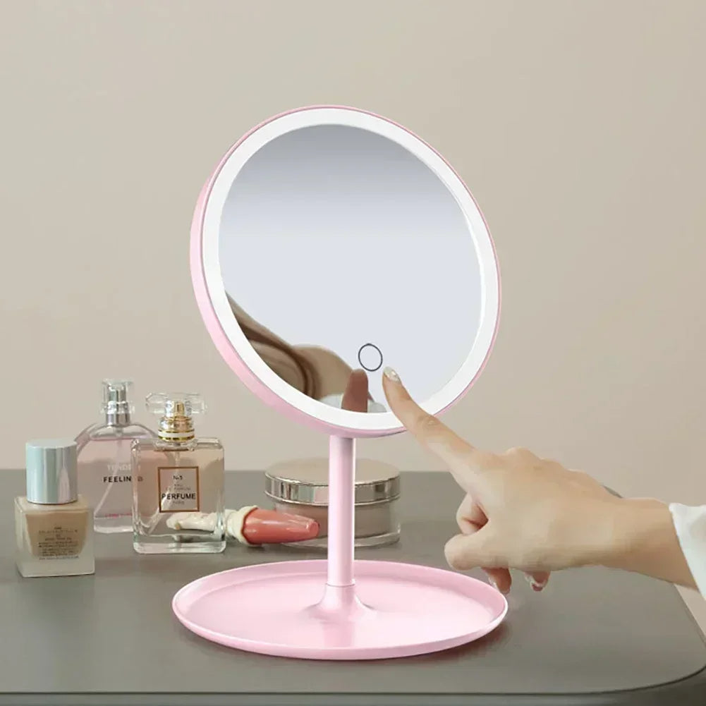 Pink vanity mirror with light control button on a table with beauty products.