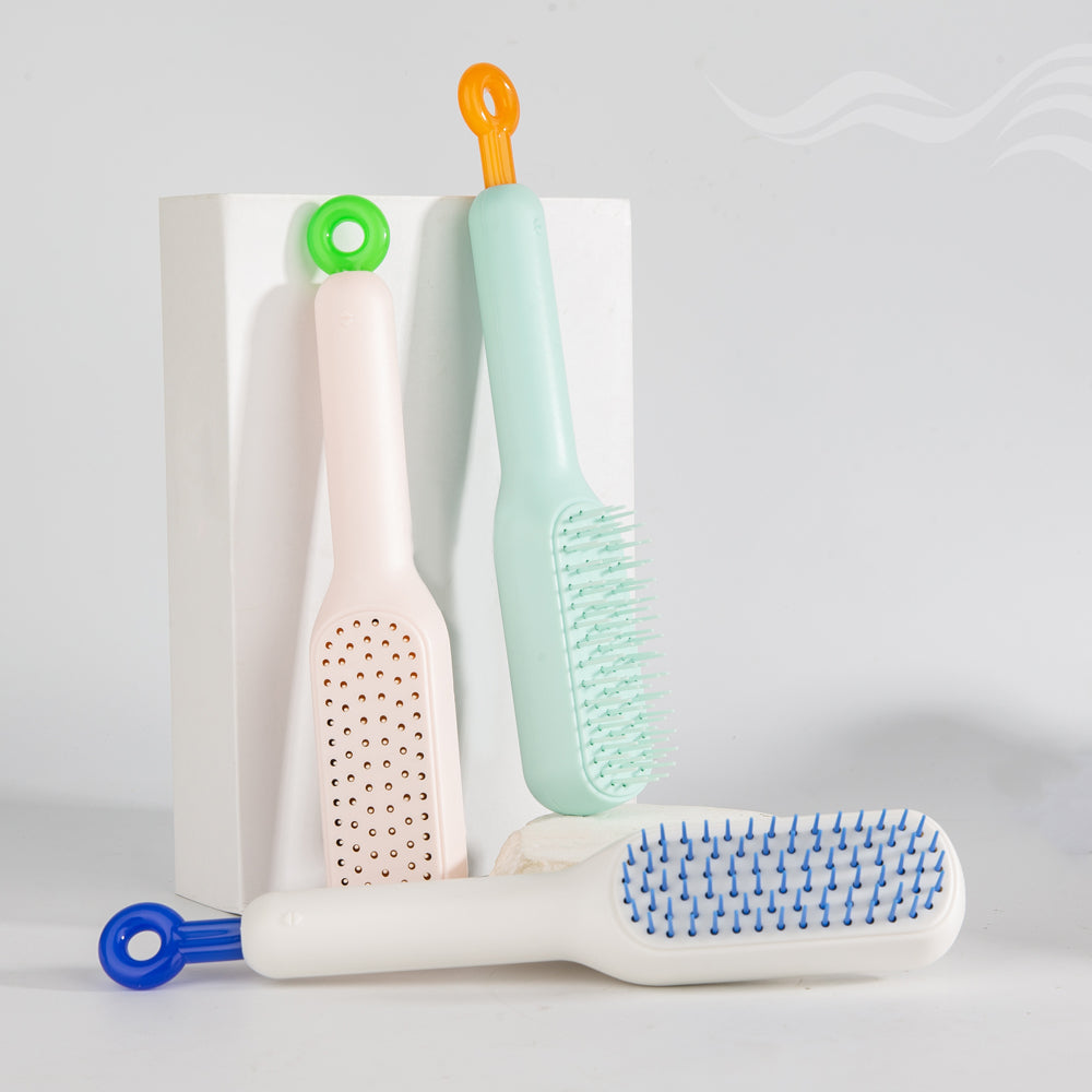 Three self cleaning hair brush brushes with different designs and colors on a white background